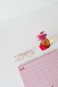 Kaboompics - Pink April Calendar with Carnation in Amber Vase and Glasses for Workspace Inspiration