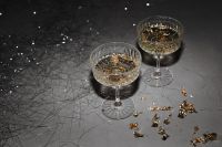 Kaboompics - Champagne Coupes and Gold Star Confetti on a Dark Party Table
