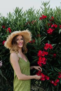 Kaboompics - Smiling Woman Posing in a Green Dress Beside Pink Flowering Shrubs