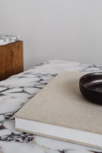 Kaboompics - Calacatta Viola Marble Side Table with Fabric-Covered Book and Black Bowl