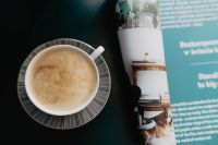Kaboompics - Coffee Cup and Rolled Magazine on a Dark Desk
