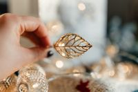 Kaboompics - Hand Holding a Gold Leaf Ornament over Christmas Lights