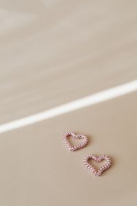 Kaboompics - Small Pink Beaded Hearts on Beige Background with Strong Diagonal Sunlight and Copy Space
