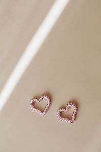 Kaboompics - Two Pearl Bead Hearts on Beige Background with Sunlit Shadow and Copy Space