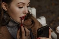 Kaboompics - Woman Applying Red Lipstick on an Autumn Park Bench