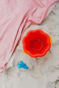 Kaboompics - Red Sand Bucket on a Pink Beach Towel for Beach Playtime and Family Travel