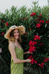 Kaboompics - Woman in a Straw Hat and Green Dress Holding Pink Flowers