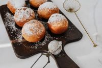 Kaboompics - Close-Up Powdered Doughnuts with Sugar Sifter on Serving Board