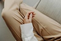 Kaboompics - Minimal Fashion Detail of Beige Trousers and Hand on Sofa