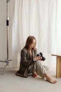 Kaboompics - Young Female Photographer Reviewing DSLR Camera While Seated