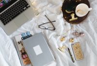 Kaboompics - Overhead Planner and Laptop Flat Lay on White Bedding with Coffee, Glasses and Gold Jewelry