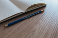 Kaboompics - Notebook with a blue pencil on a wooden desk