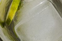 Kaboompics - Close-Up Ice Cube beside Lime Peel in Clear Water, Abstract Citrus Drink Background