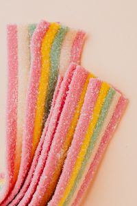 Kaboompics - Pastel Rainbow Sour Belts on Beige, Diagonal Candy Flat Lay