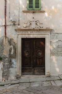 Kaboompics - Weathered Wooden Door with Carved Stone Lintel and Green Shutters