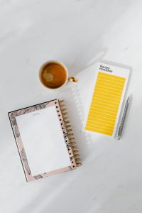 Top view of a marble desk with coffee, notebooks and pen