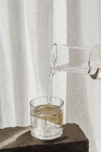 Kaboompics - Pitcher Pouring Water Into a Lemon Water Glass