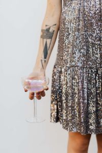 Kaboompics - Tattooed Arm Holding Champagne Flute beside Sequin Dress