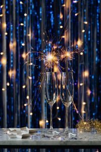 Kaboompics - Two Champagne Flutes with Lit Sparklers on Blue Silver Tinsel