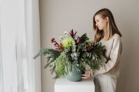 Kaboompics - Woman Holding a Lush Christmas Greenery Arrangement