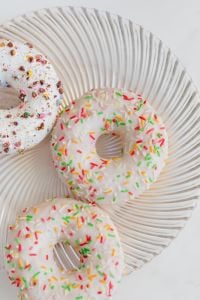 Kaboompics - Close-Up of Sprinkle-Covered Donuts on a Ribbed Glass Plate