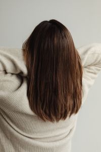 Kaboompics - Straight Medium-Length Brown Hair with Raised Arms in a Beige Sweater