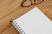 Kaboompics - Close-Up of Eyeglasses Beside a Blank Notebook on a Wood Desk, Copy Space