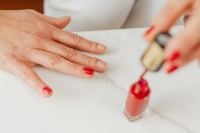 Kaboompics - Applying Red Nail Polish to a Fingernail on White Marble for At-Home Manicure Content