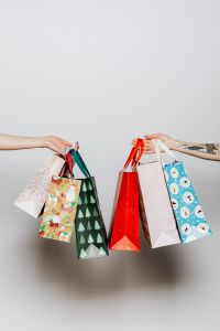 Kaboompics - Hands Exchanging Patterned Christmas Shopping Bags, Full Vertical White Studio Composition