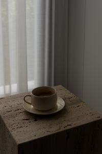 Kaboompics - Moody Coffee Cup on Travertine Table by Sheer Curtains