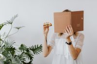 Kaboompics - Woman Eating Burger Behind Open Notebook at Work