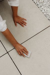 Kaboompics - Woman Cleaning the Edge of a Tiled Floor Beside White Stones