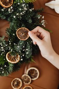 Kaboompics - Close Up of Hand Decorating Dried Orange Christmas Wreath