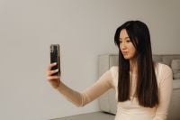 Kaboompics - Woman Holding Her Phone for a Seated Self-Portrait in a Neutral Living Room