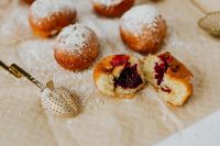 Kaboompics - Cherry Jam Filled Polish Paczki Doughnuts Cut Open with Powdered Sugar, Overhead Dessert Still Life
