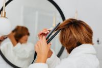 Kaboompics - Over-the-Shoulder View of a Woman Straightening Her Hair in a Bathroom Mirror