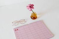 Kaboompics - Pink Calendar, Planner, Glasses and Carnation in Amber Vase for Desk Styling
