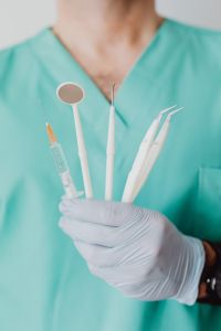 Kaboompics - Gloved Hand Holding Dental Tools Against Scrubs