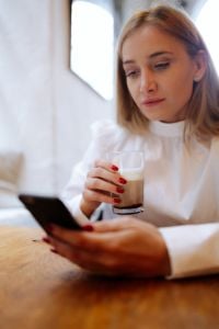 Kaboompics - Blonde Woman Holding Iced Coffee and Smartphone