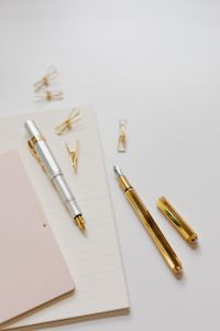 Kaboompics - Silver and Black Fountain Pens with Gold Clips beside Pink Notepad on a Lined Notebook