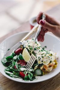 Close up image of young woman eating classic breakfast at restaurant