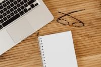 Kaboompics - Laptop, Eyeglasses and Blank Notebook on a Light Oak Desk, Neutral Workspace Flat Lay