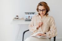 Kaboompics - Woman Writing in Notebook at Laptop Desk in Home Office