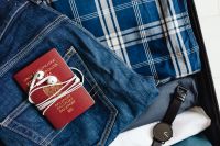 Kaboompics - Macro Travel Essentials: Passport, Earbuds and Wristwatch on Denim in Suitcase