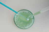 Kaboompics - Pipettes Transferring Liquid Over a Green Petri Dish