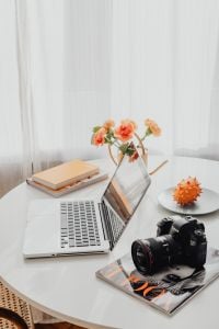 Kaboompics - Laptop and DSLR Camera on a Round Desk with Carnations