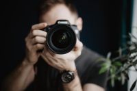 Kaboompics - Photographer Looking Through a DSLR Camera with Greenery Behind