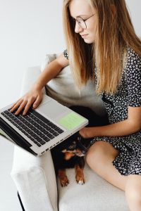 Kaboompics - Close Up of Student Working on Laptop with Dog