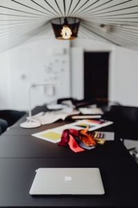 Kaboompics - Open MacBook on a Black Desk with Designer Fabric Samples in the Background