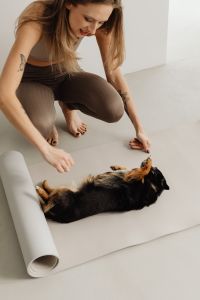 Kaboompics - Woman Kneeling Beside a Dog Lying on a Yoga Mat